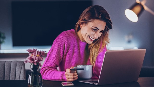 Image of woman looking at laptop with coffee mug in hand