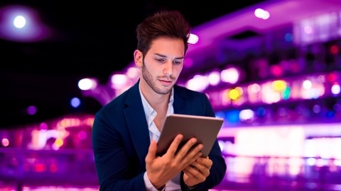 Image of man holding tablet outside at night